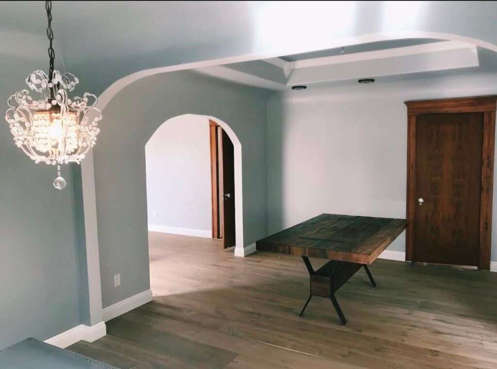 Dining-room-with-chandelier-arched-doorway-and-rustic-wooden-table