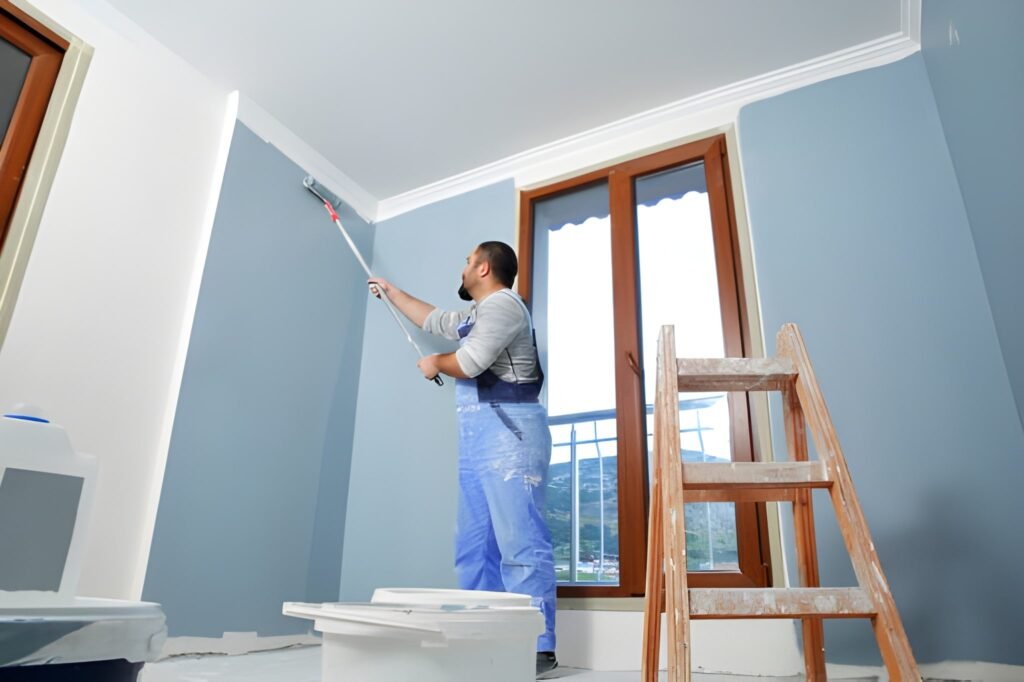 Painter man at work takes the color with paint roller from the bucket.