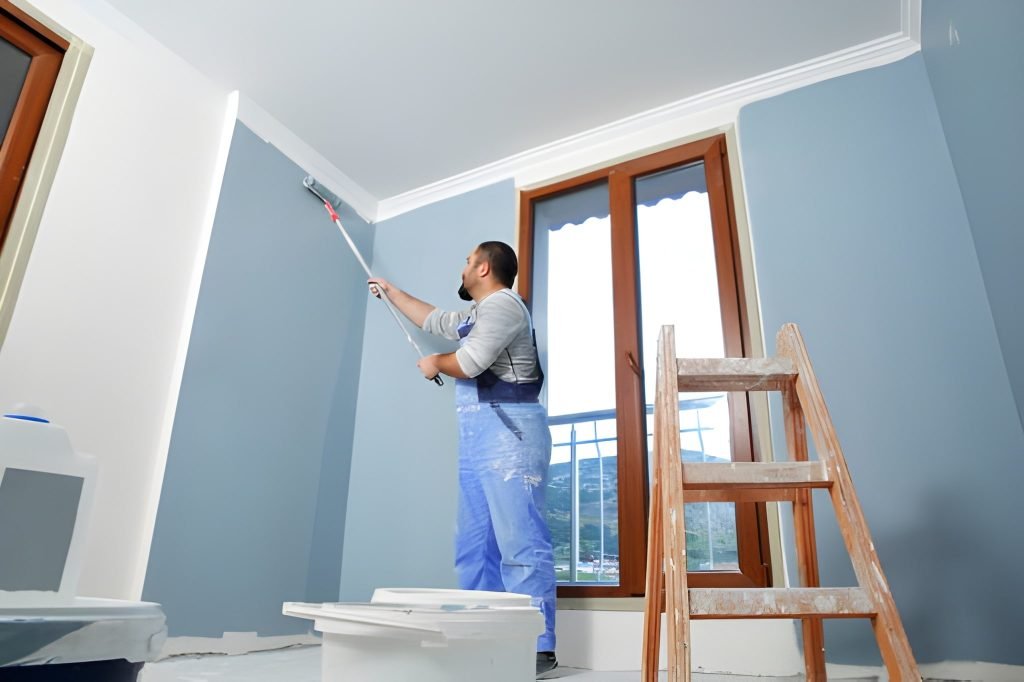 Painter man at work takes the color with paint roller from the bucket