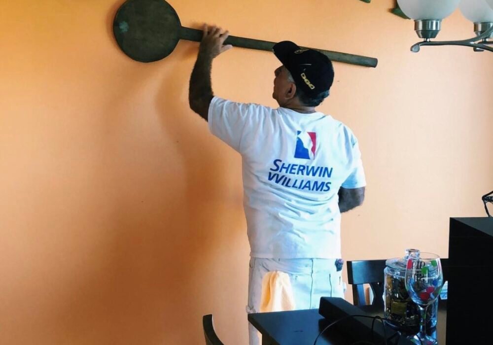Painter working on orange kitchen wall