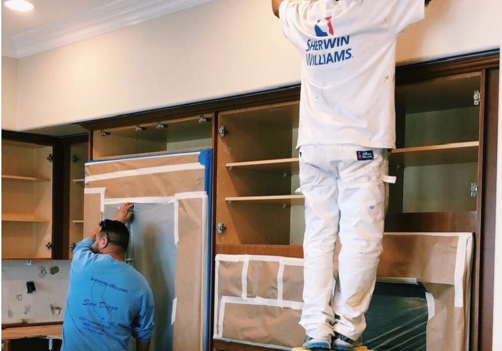 Painters prepping kitchen cabinets for painting