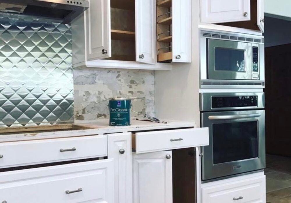 Kitchen renovation in progress with white cabinets being repainted