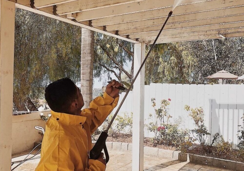 person power washing wooden patio ceiling