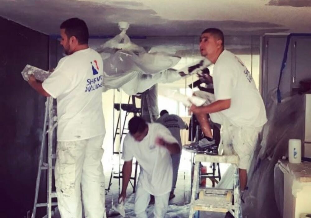 workers repairing and painting interior ceiling