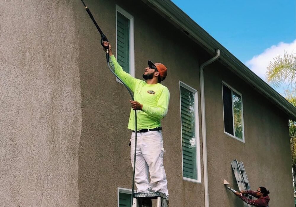workers pressure washing exterior house wall